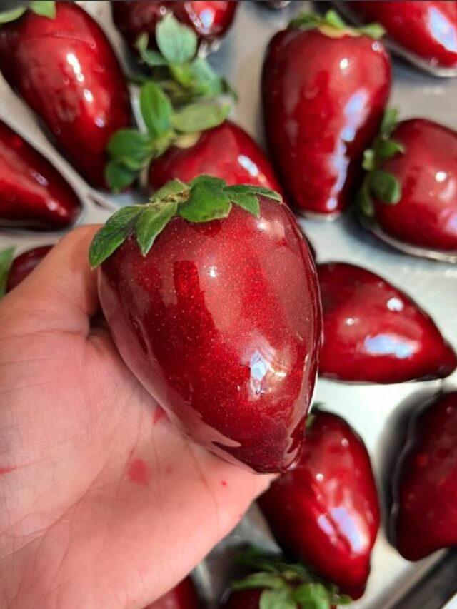 Mão segurando um morango do amor.